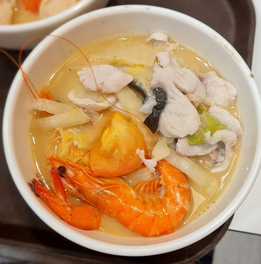 A close-up of a delicious bowl of seafood soup with fish slices, shrimp, and vegetables.