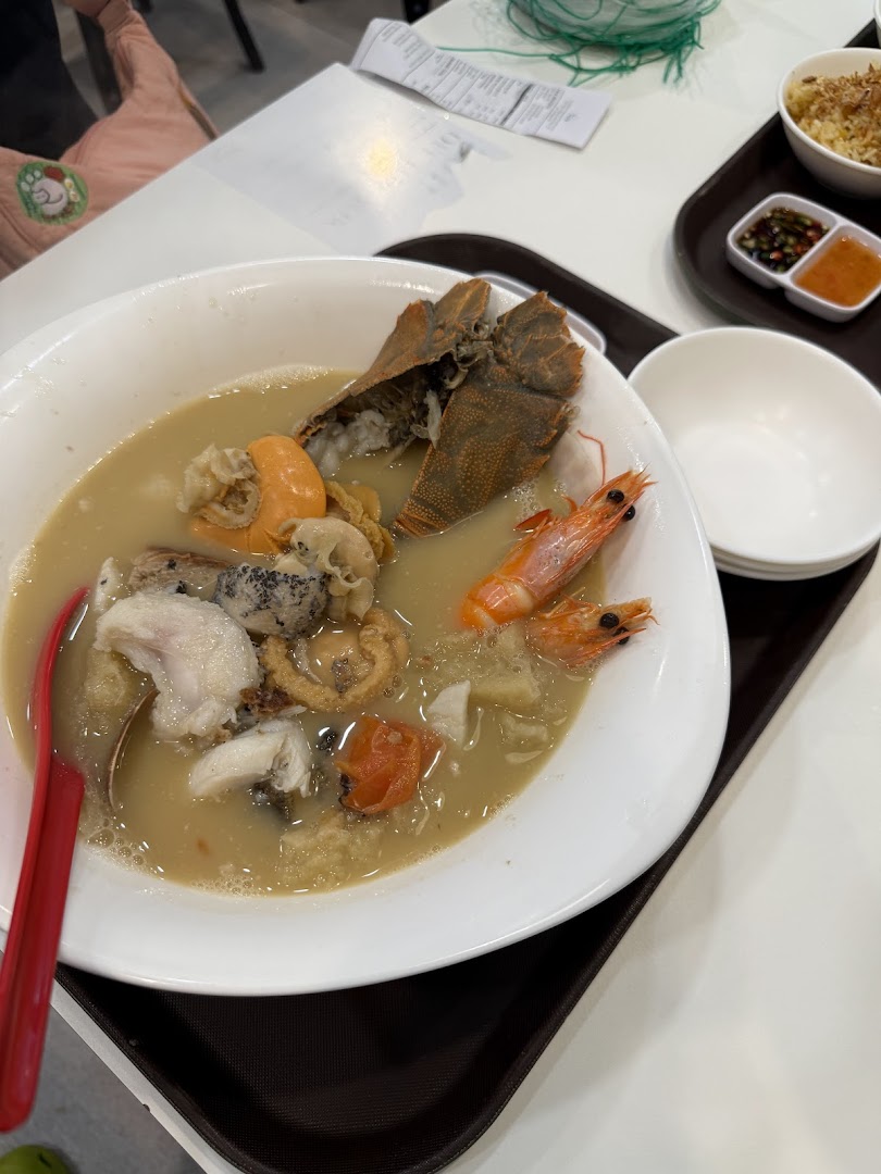 A large bowl of gourmet seafood soup featuring prawns, fish, and a slipper lobster.