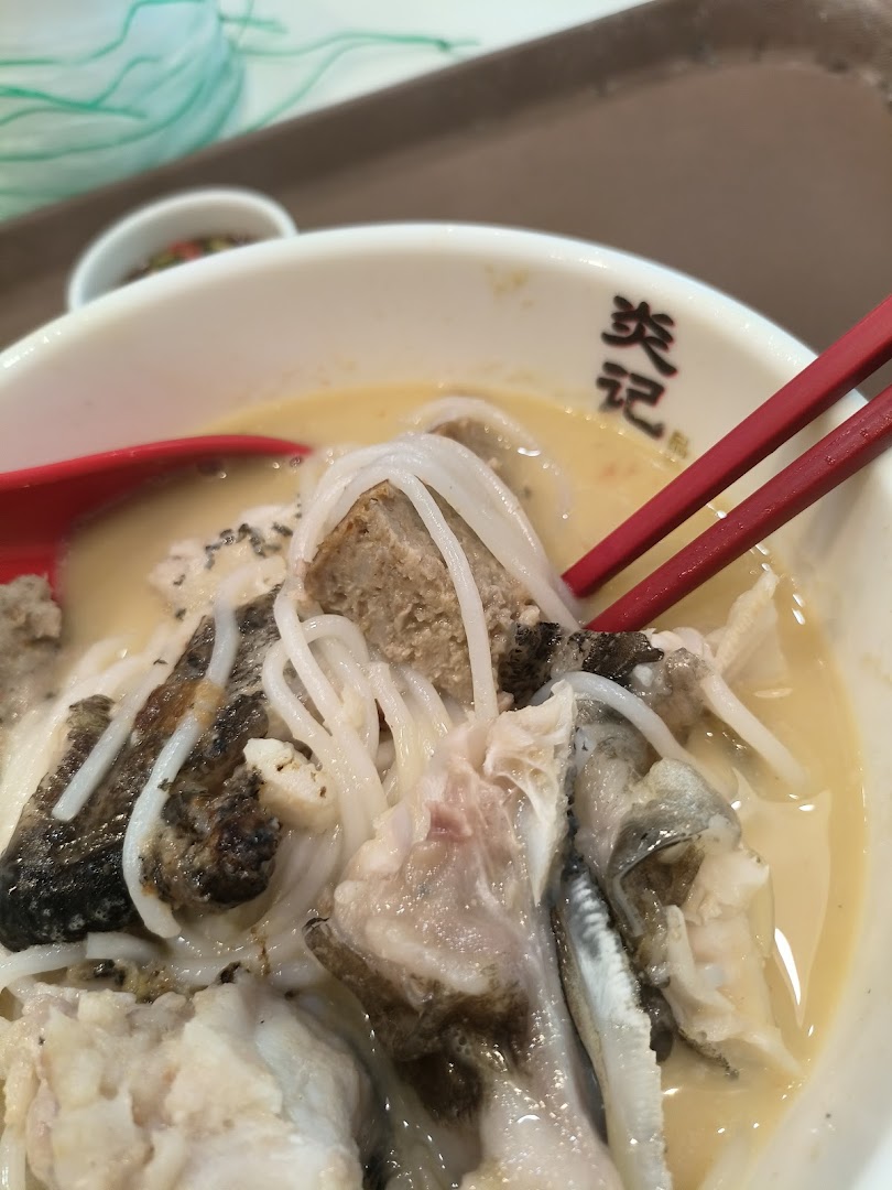 A close-up of a delicious bowl of seafood soup with noodles and fish, served with chopsticks.