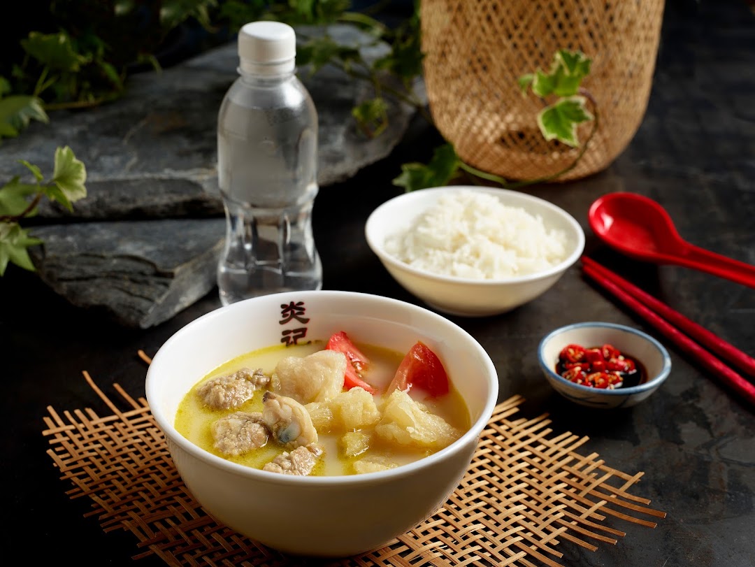 A hearty bowl of seafood soup with rice, water, and chili, ready to be enjoyed.