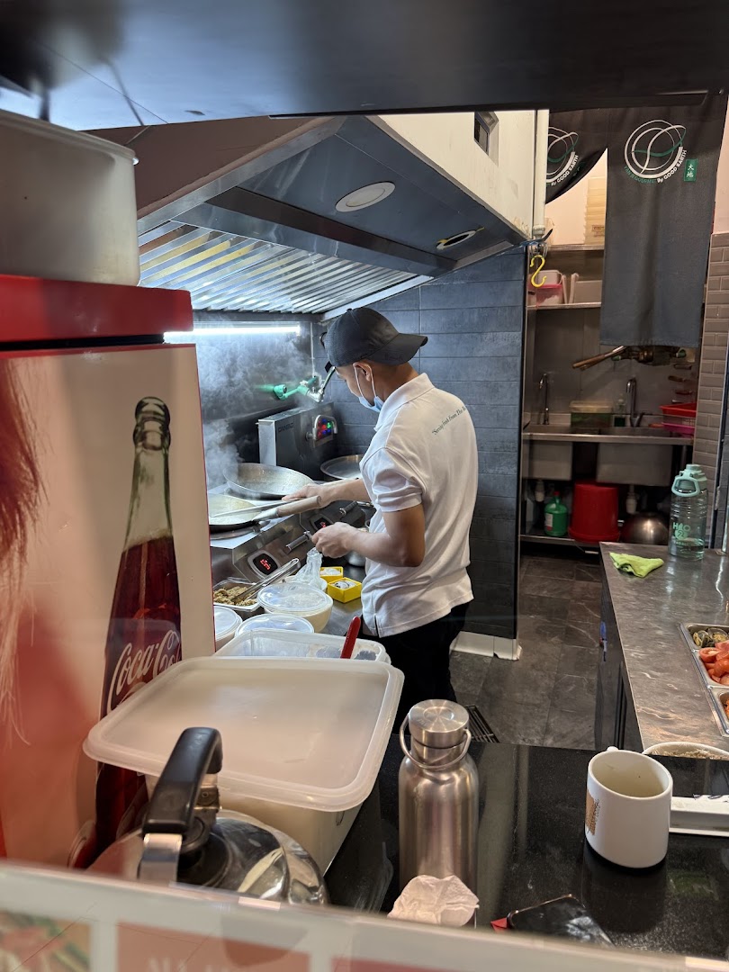 A chef prepares a dish in the kitchen of Yan Ji Gourmet Seafood Soup, showcasing fresh cooking.