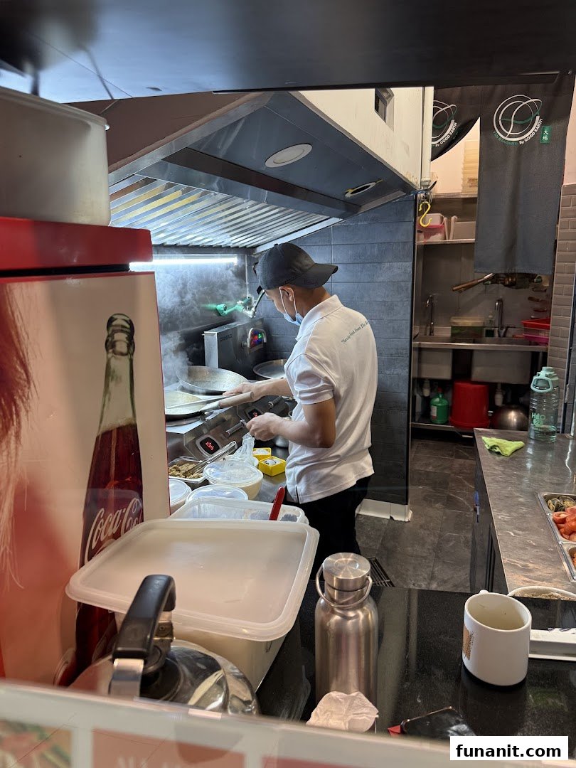 A chef prepares a dish in the kitchen of Yan Ji Gourmet Seafood Soup, showcasing fresh cooking.