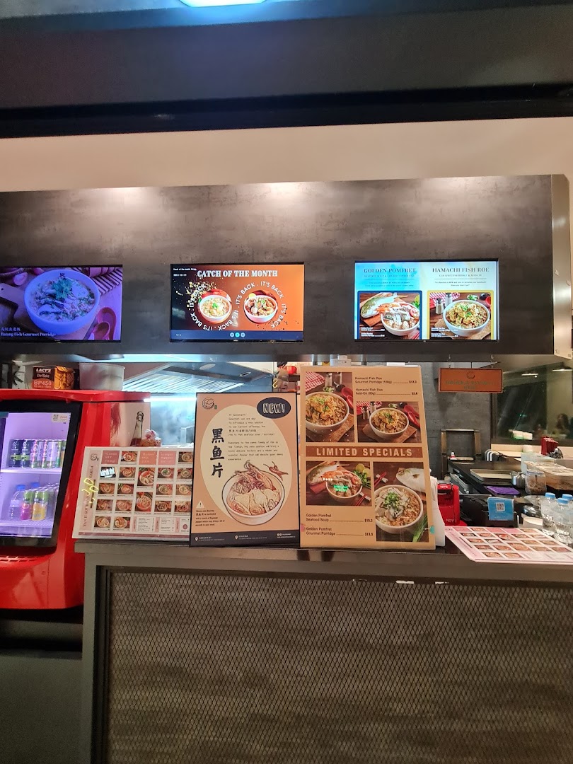 A vibrant counter at Yan Ji Gourmet Seafood Soup, showcasing digital menus and physical boards with gourmet seafood dishes and specials.