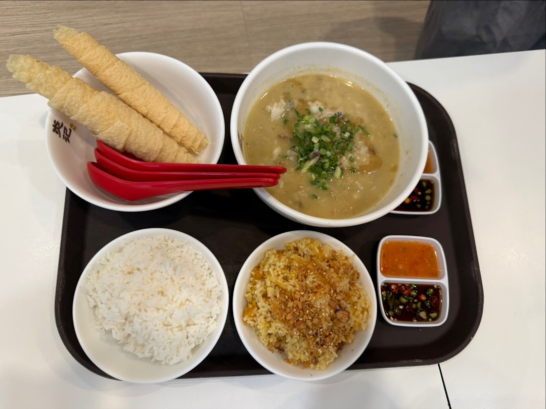 A delicious seafood soup set with rice, fried rice, crispy rolls, and various dipping sauces on a tray.