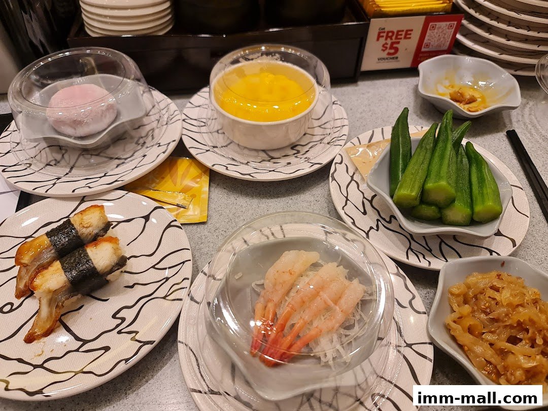 A table filled with various sushi dishes, including eel sushi, shrimp, mochi, and okra.