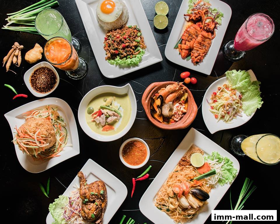 A vibrant overhead shot of various Thai dishes and drinks arranged on a dark surface.