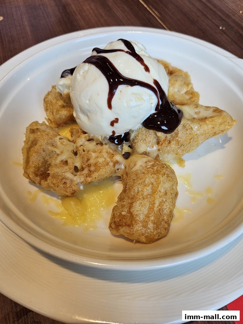 A close-up of a dessert with ice cream, chocolate sauce, and fried batter.