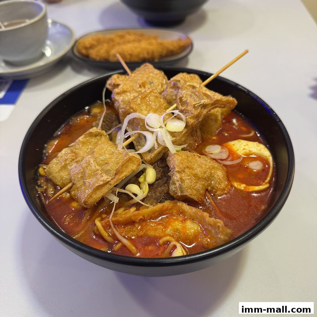A close-up of a steaming bowl of hotpot with various ingredients and a side of fried food.