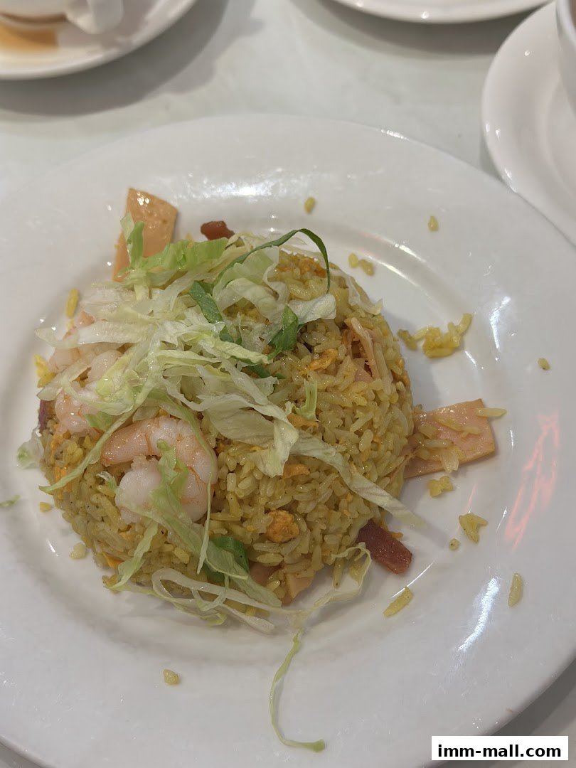 A plate of fried rice with shrimp, ham, and shredded lettuce.