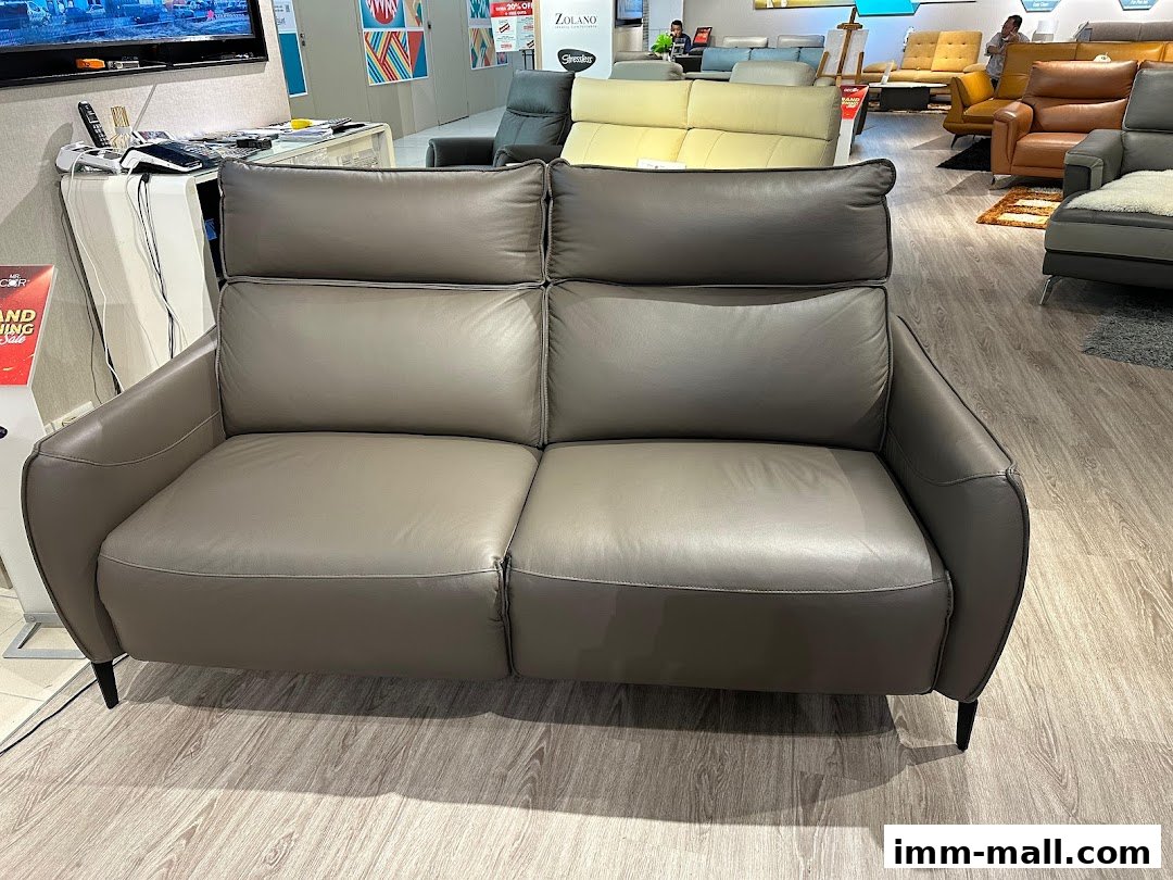 A modern grey leather sofa displayed in a furniture showroom with other sofas in the background.