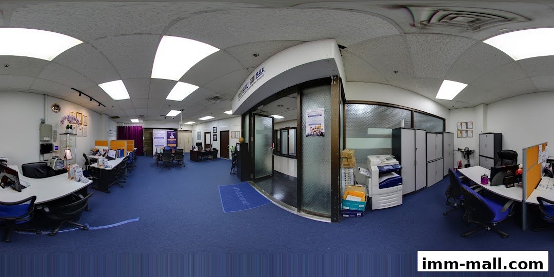 Interior view of an office space with desks, chairs, computers, and a reception area.