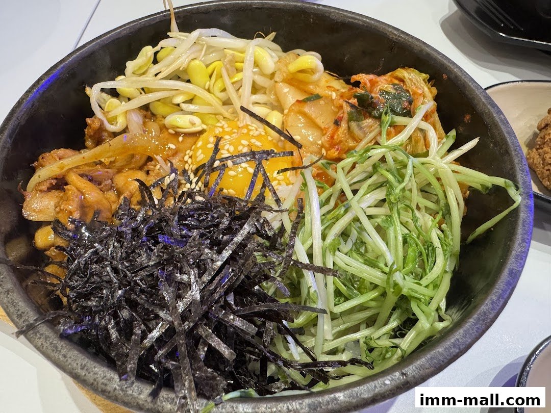 A close-up of a Korean bibimbap dish with rice, meat, vegetables, and a fried egg.