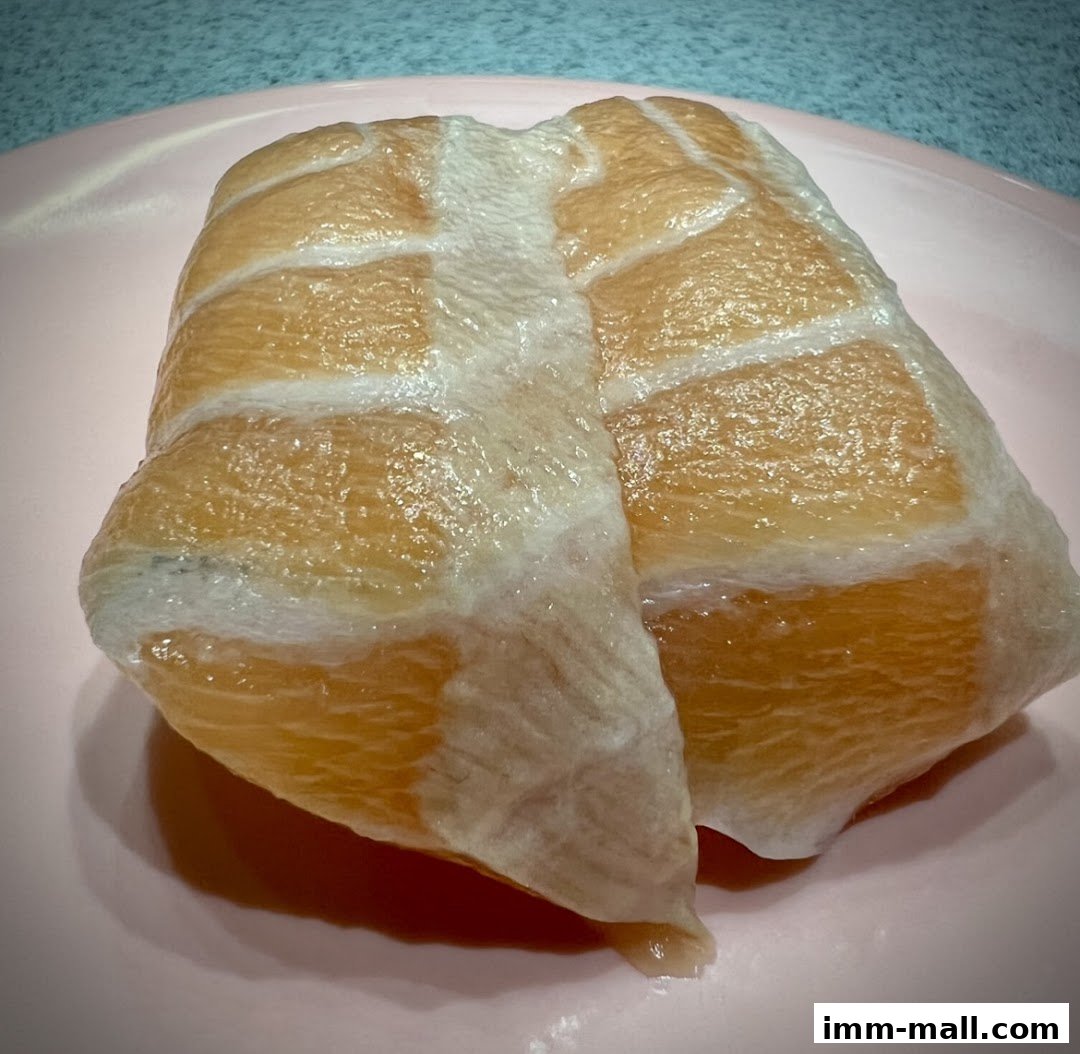 A close-up shot of a piece of salmon sushi on a pink plate.