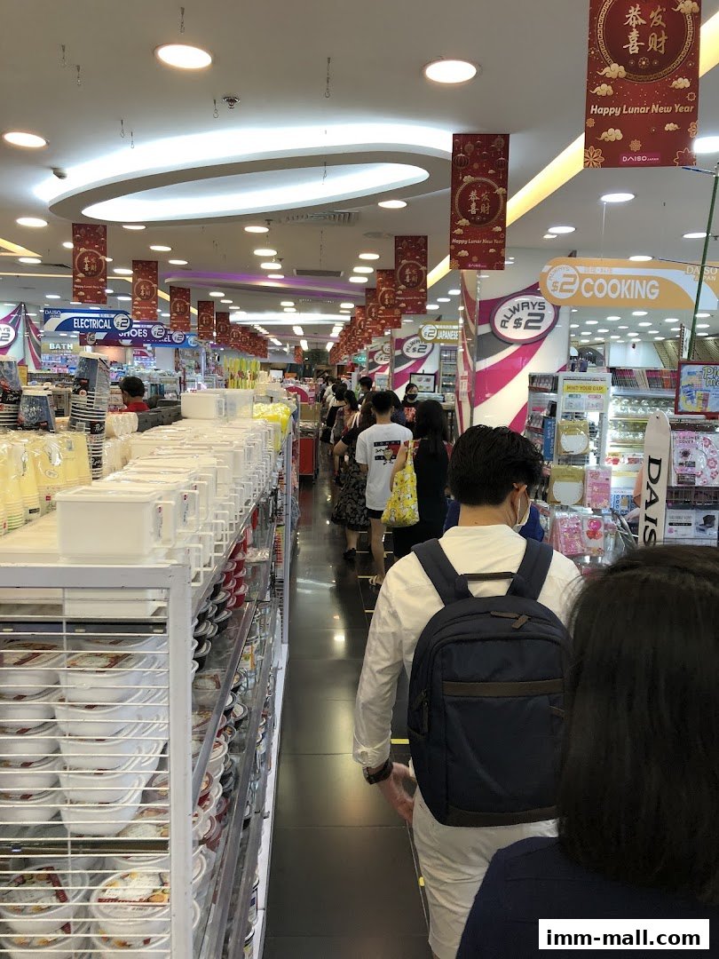 A busy aisle inside a Daiso store with shoppers and merchandise displayed on shelves.