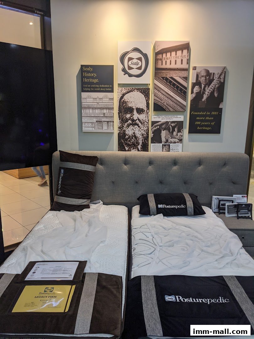 Two beds are displayed with Sealy branding and historical imagery on the wall.