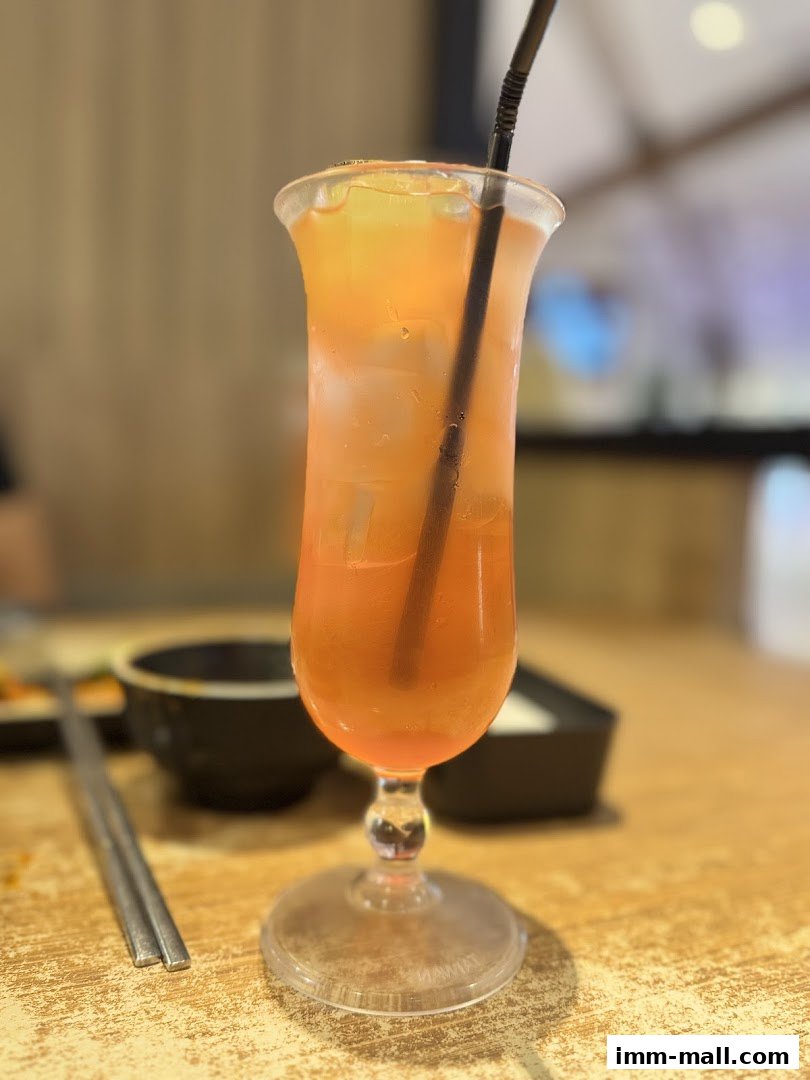 A refreshing iced tea with a straw in a tall glass on a wooden table.