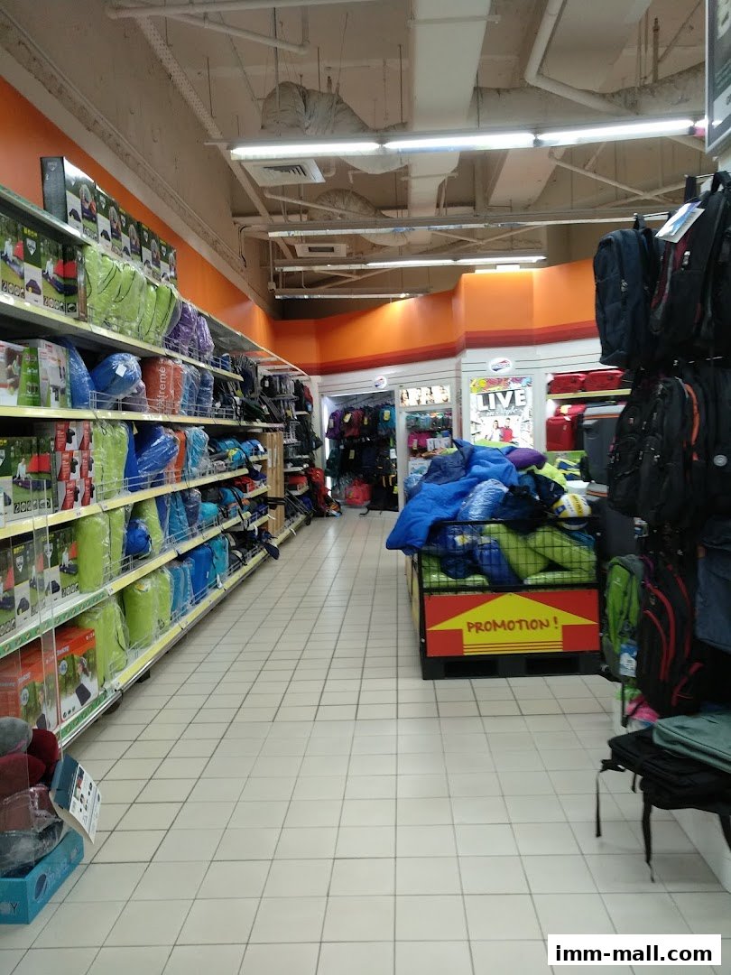 Aisle in a supermarket with shelves stocked with bags and outdoor gear.