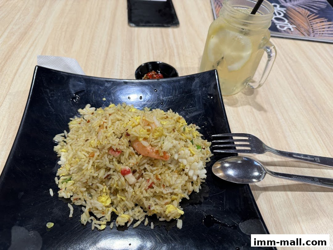 A plate of seafood fried rice with a refreshing lemon drink and cutlery.