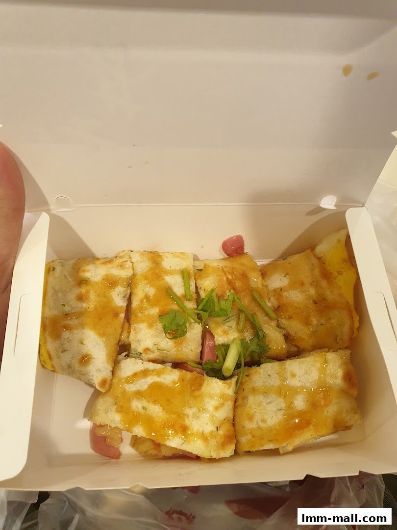 A white takeout box filled with sliced Taiwanese street snacks, garnished with cilantro.