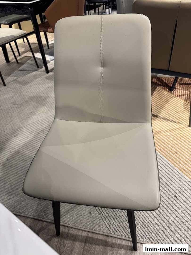 A light gray upholstered dining chair with a tufted back and dark metal legs.