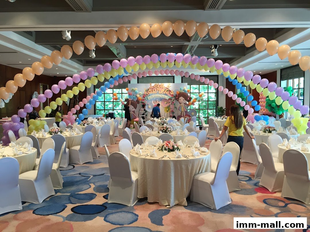 A beautifully decorated event space with balloon arches and set tables for a party.