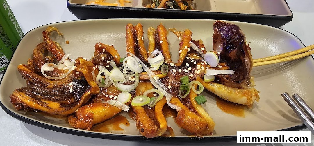 A plate of glazed squid tentacles with sesame seeds and green onions.