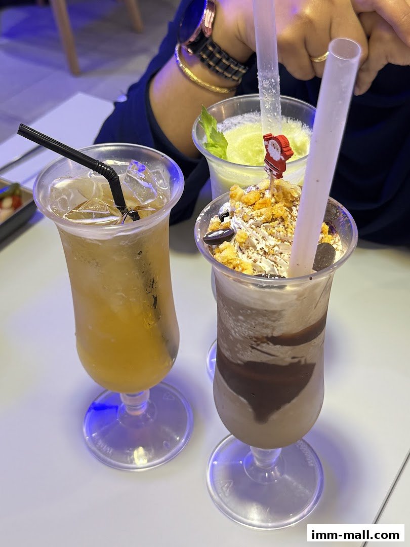Three refreshing drinks, including a chocolate milkshake and two iced beverages, are displayed on a white table.