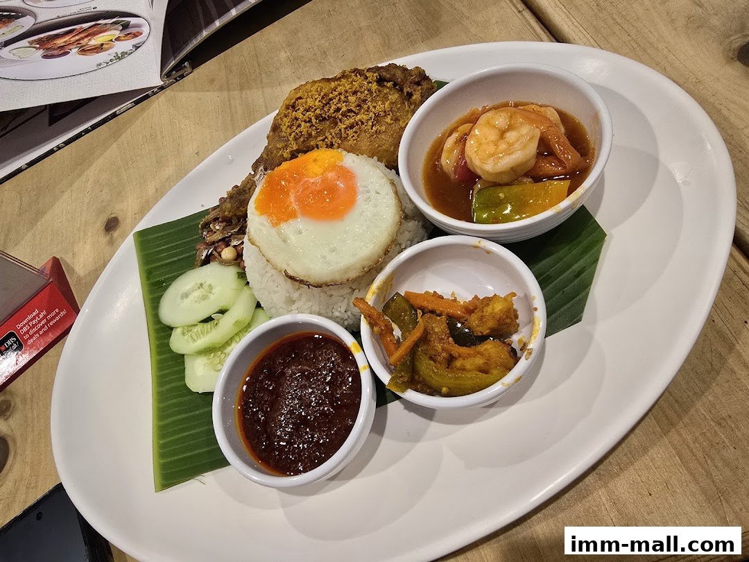 A plate of nasi lemak with fried chicken, sunny-side-up egg, sambal, and side dishes.