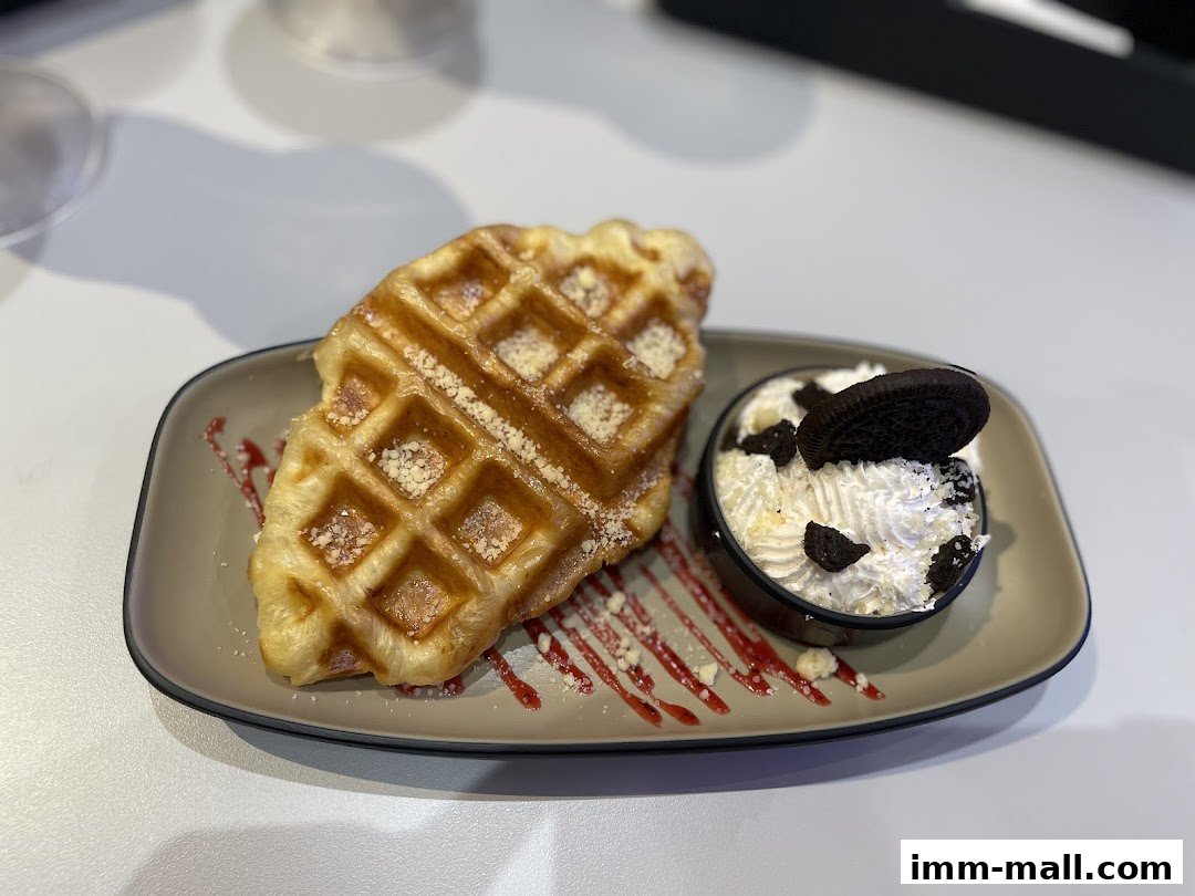 A delicious waffle with whipped cream and Oreo cookie crumbs served on a plate.