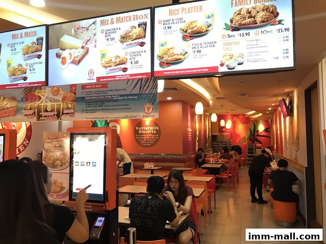 Interior view of a Popeyes restaurant with digital menus displaying food items and customers dining.