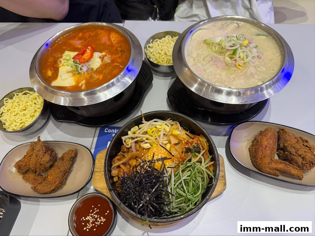 A table laden with Korean dishes including hot pots, fried chicken, and bibimbap.