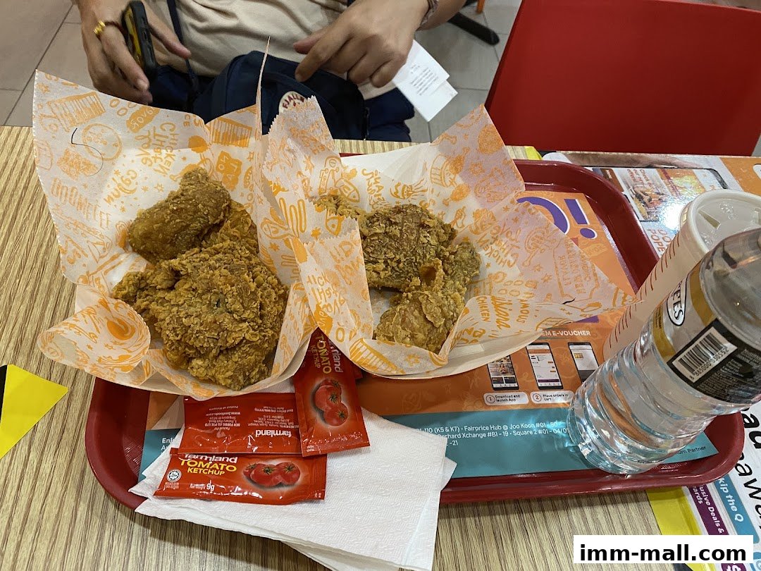 A tray of Popeyes fried chicken with ketchup packets and a bottle of water.