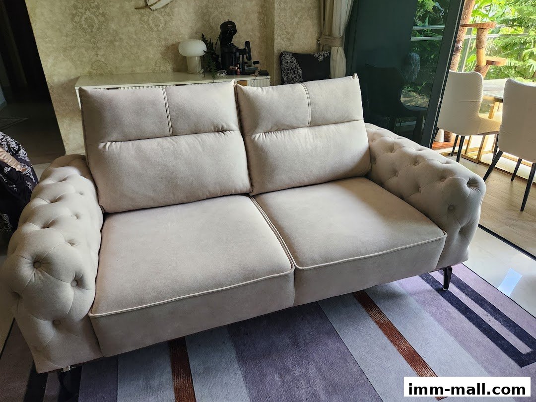 A plush, cream-colored sofa with tufted arms and back, displayed in a well-lit room.