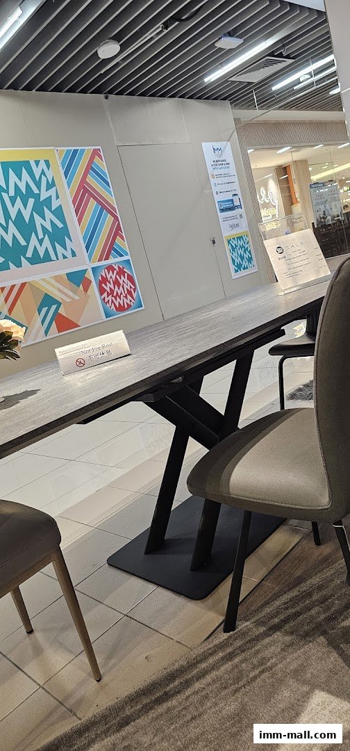 A modern dining table and chairs are displayed in a furniture store with colorful wall art.