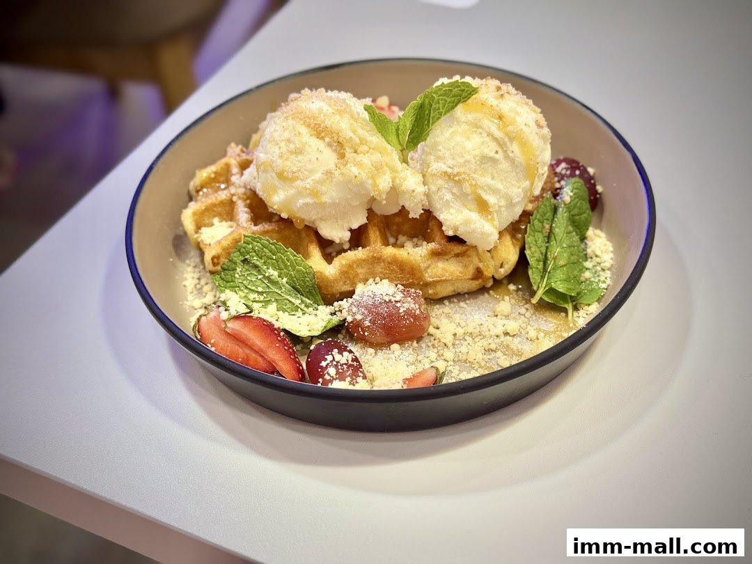 A delicious waffle topped with ice cream, fruits, and mint leaves served in a bowl.