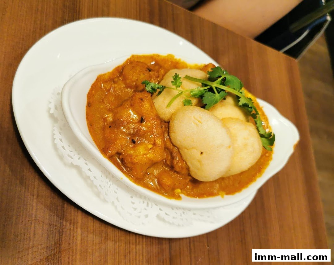 A close-up of a delicious curry dish with fluffy dumplings and fresh cilantro garnish.