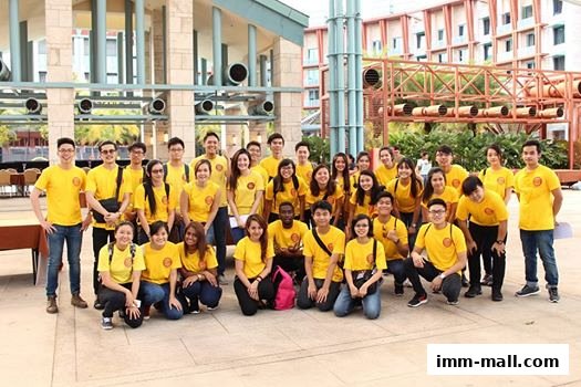 A large group of people, mostly young adults, wearing matching yellow t-shirts with a circular logo.