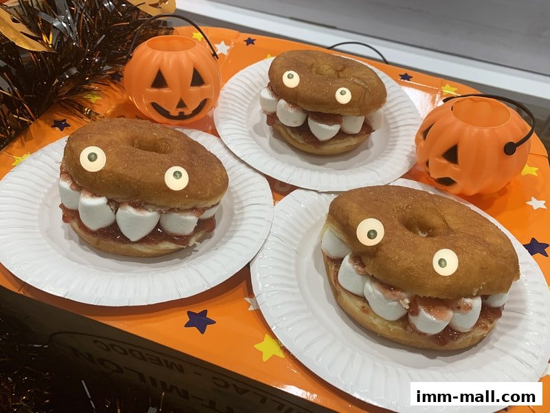 Three Halloween-themed donuts decorated to look like monsters with marshmallow teeth and candy eyes.