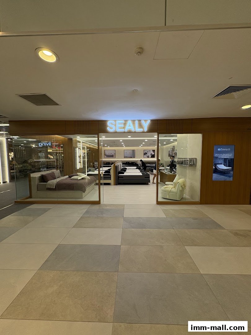The entrance to a Sealy Sleep Boutique, showcasing beds and a comfortable armchair.