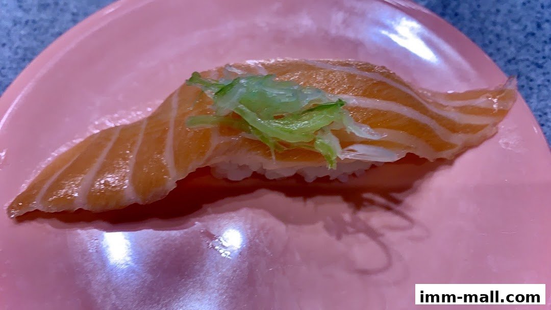 A close-up shot of a delicious salmon sushi nigiri on a pink plate.