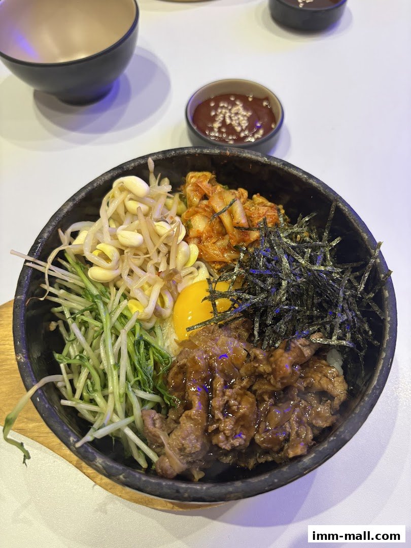 A close-up of a Korean bibimbap dish with beef, vegetables, egg, and seaweed.