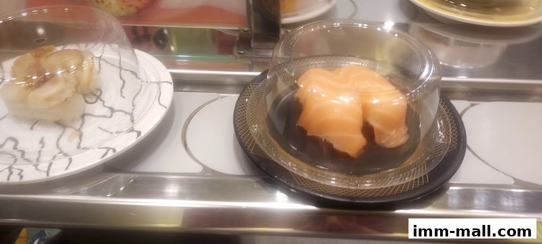 Close-up of conveyor belt sushi with salmon and scallop nigiri.