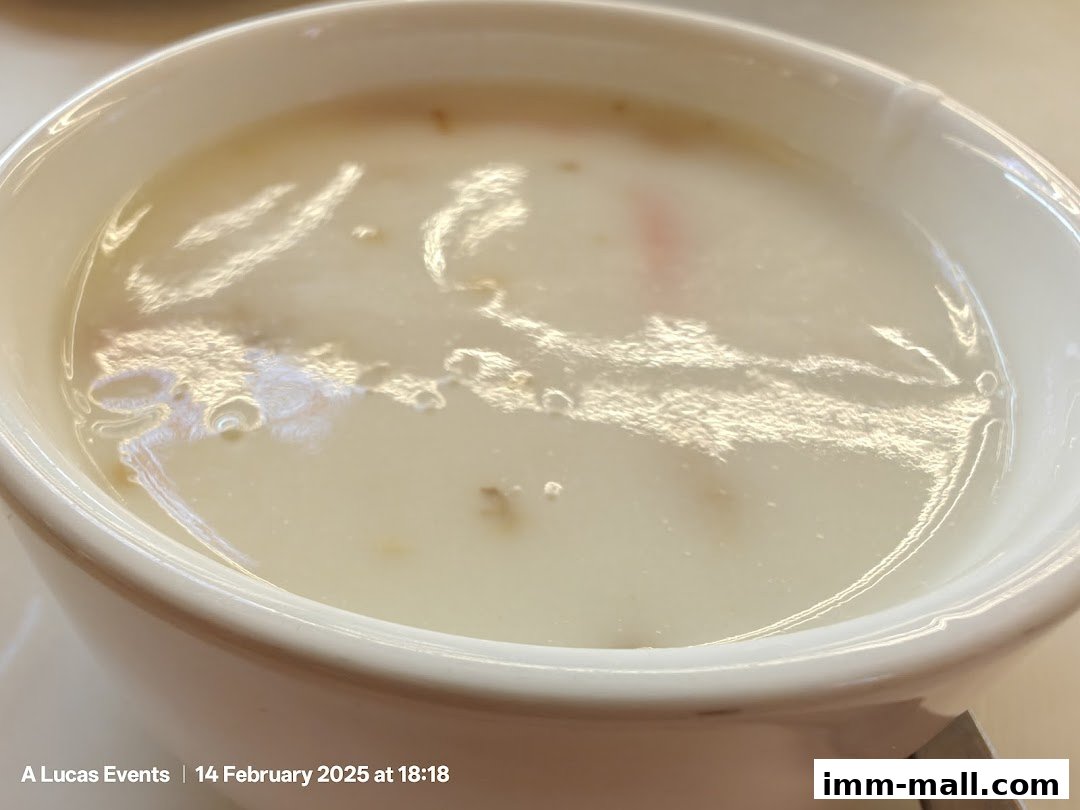 A close-up shot of a creamy soup in a white bowl, with reflections on the surface.