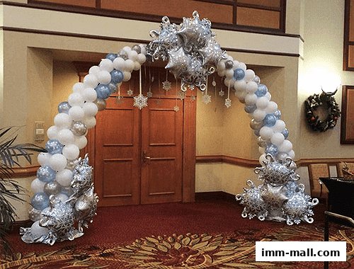 A festive balloon arch with snowflake and star accents in white and blue.