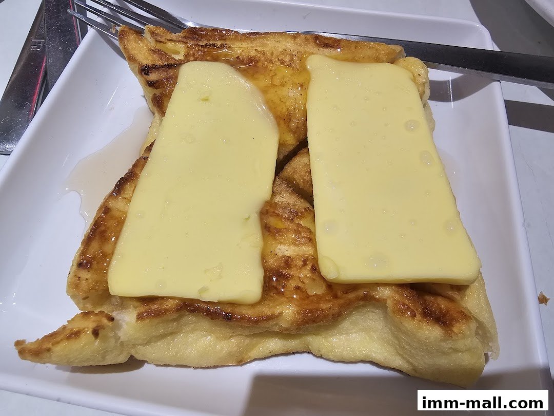 A close-up shot of golden-brown French toast topped with melting butter and syrup.