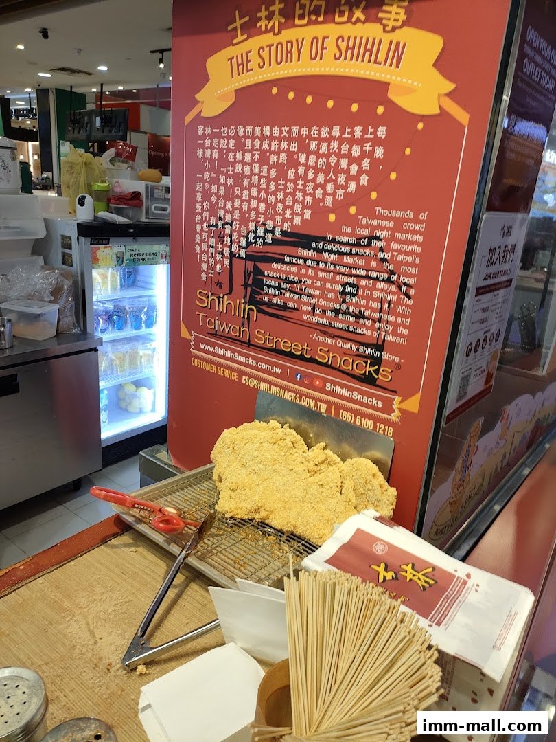 A display of Taiwanese street food, featuring a large fried chicken cutlet and promotional materials.