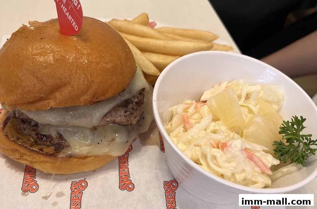 A juicy burger with melted cheese, fries, and coleslaw with pineapple chunks.