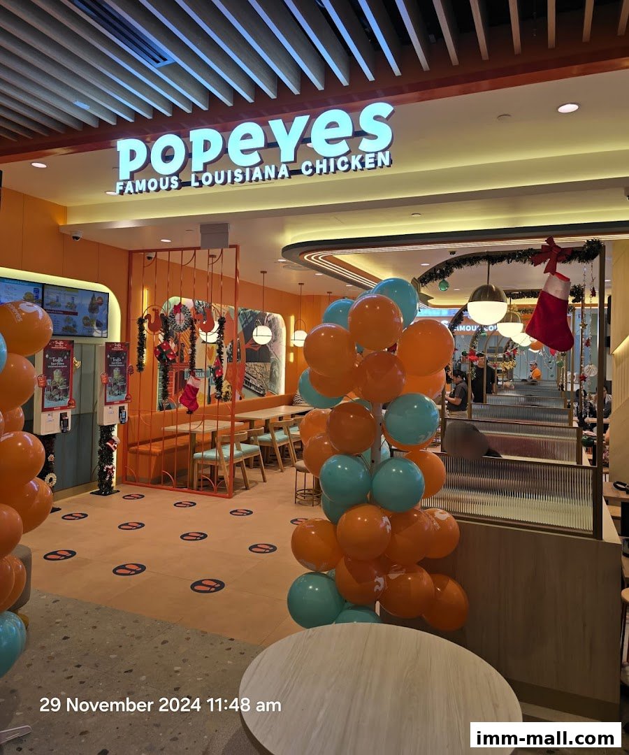 The entrance of Popeyes Famous Louisiana Chicken, decorated with orange and teal balloons and festive Christmas stockings.