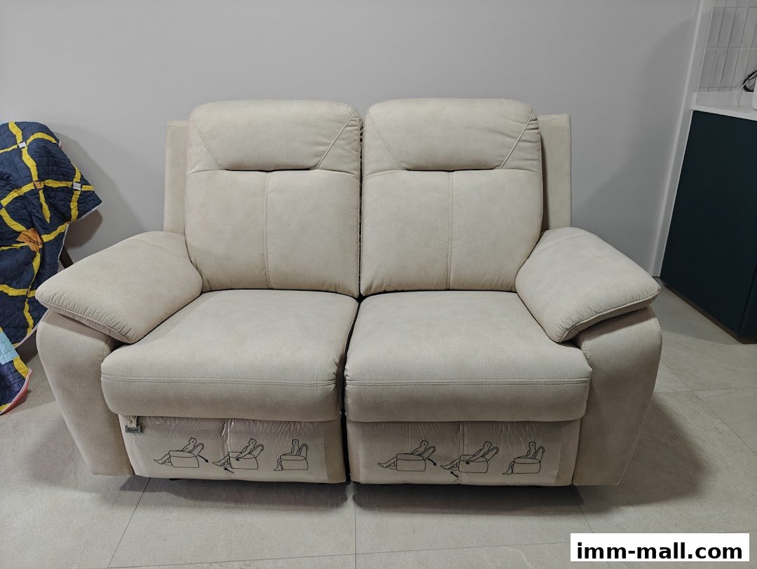 A comfortable, light-colored recliner sofa with plush cushions and reclining mechanism indicators.
