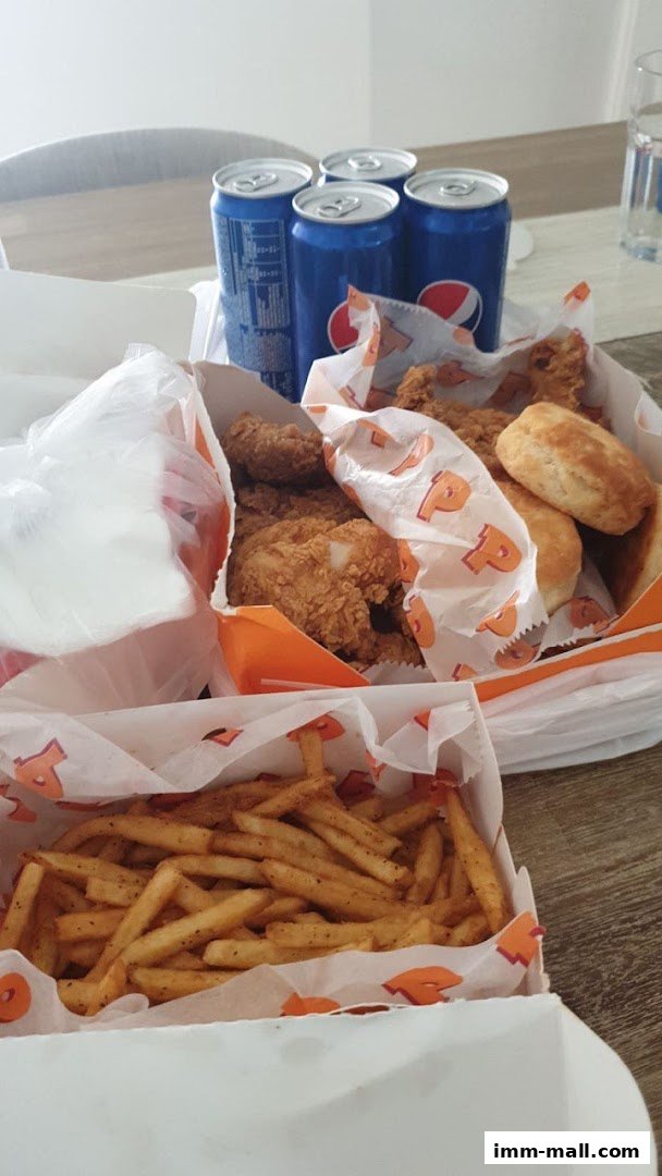 A spread of Popeyes fried chicken, fries, biscuits, and Pepsi cans.